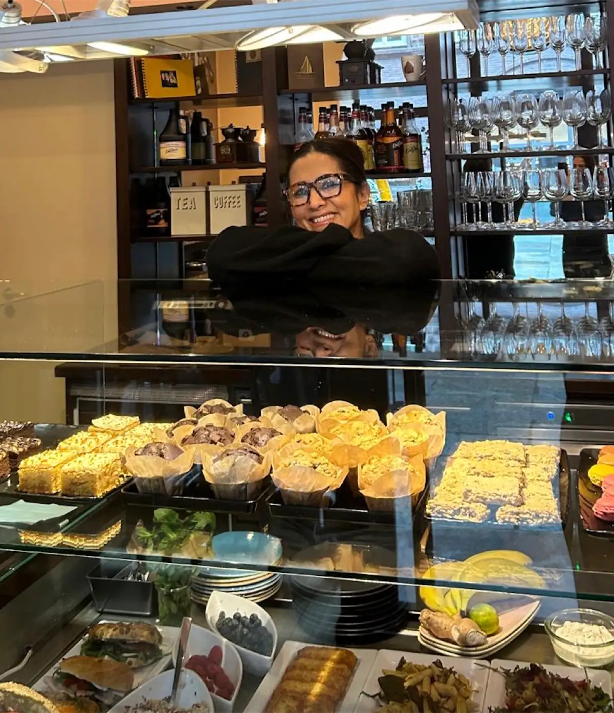 Wajia Ghazi hinter der Vitrine mit Kuchen, Muffins und belegten Broten.